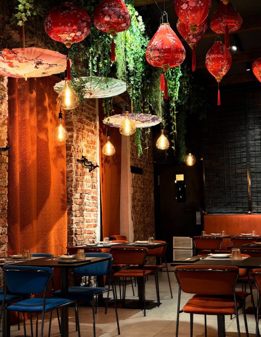 Sala con archi in mattoni, ombrelli sospesi e lampadine vintage