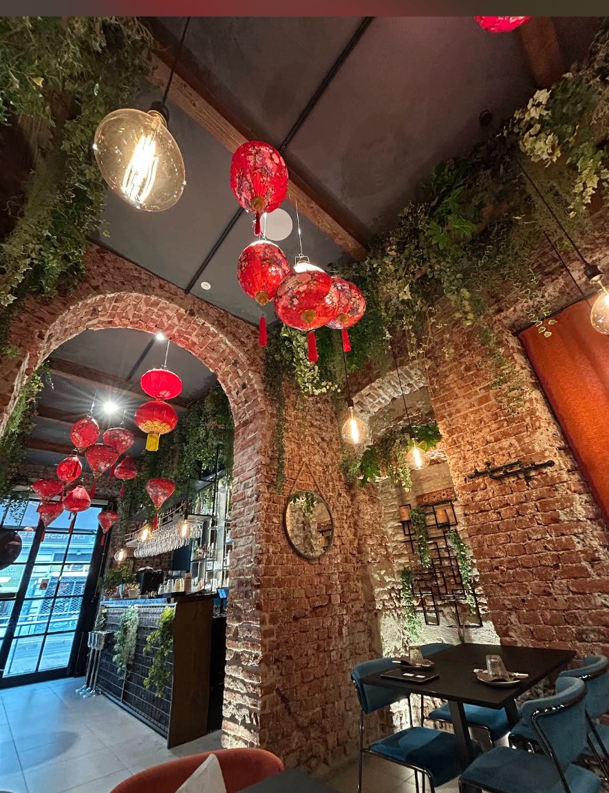 Interni di Oh! My Bao Milano con lanterne rosse, archi in mattoni e luce calda